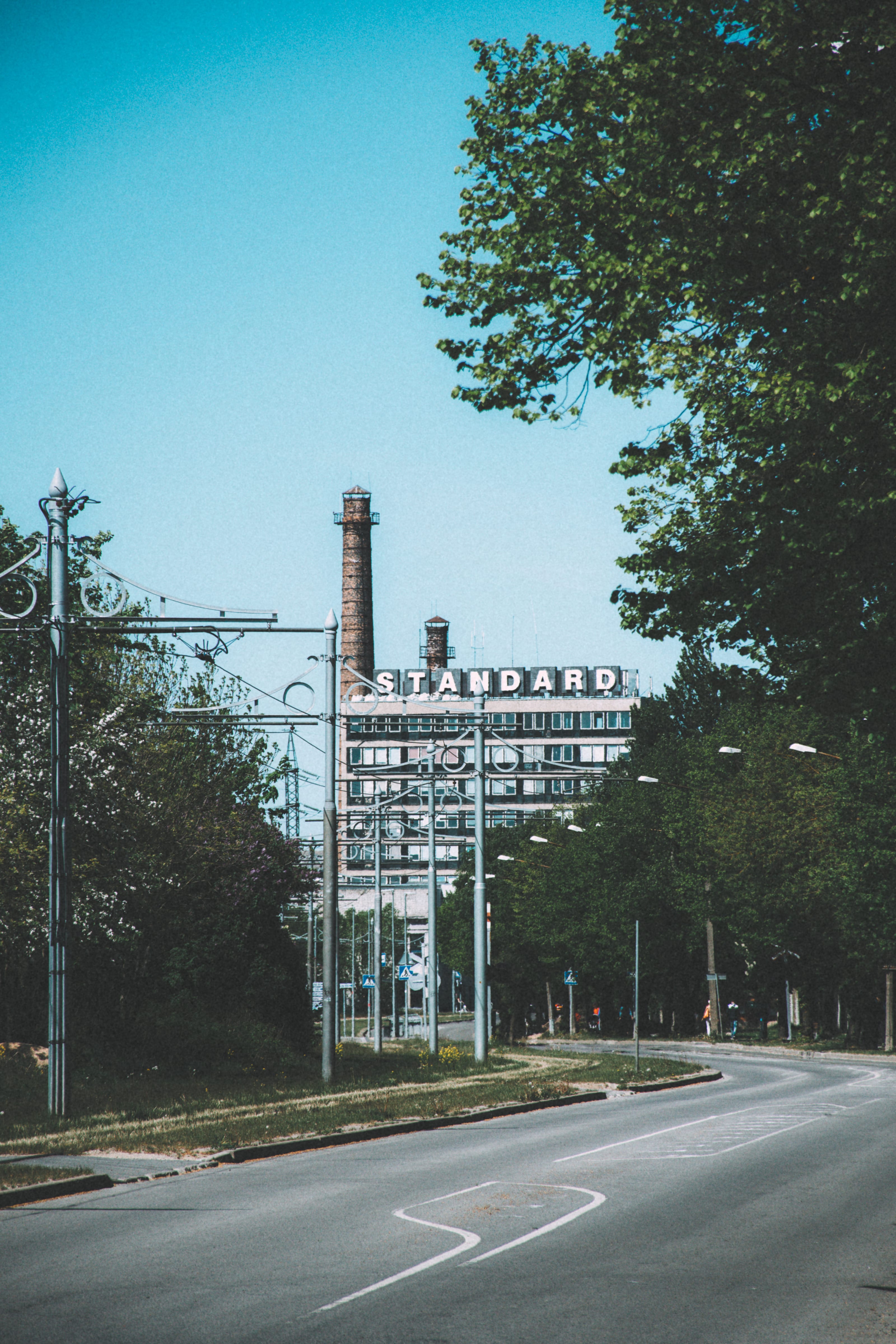 Quiet industrial street leading toward a distant chimney in Kopli, Tallinn, Estonia.