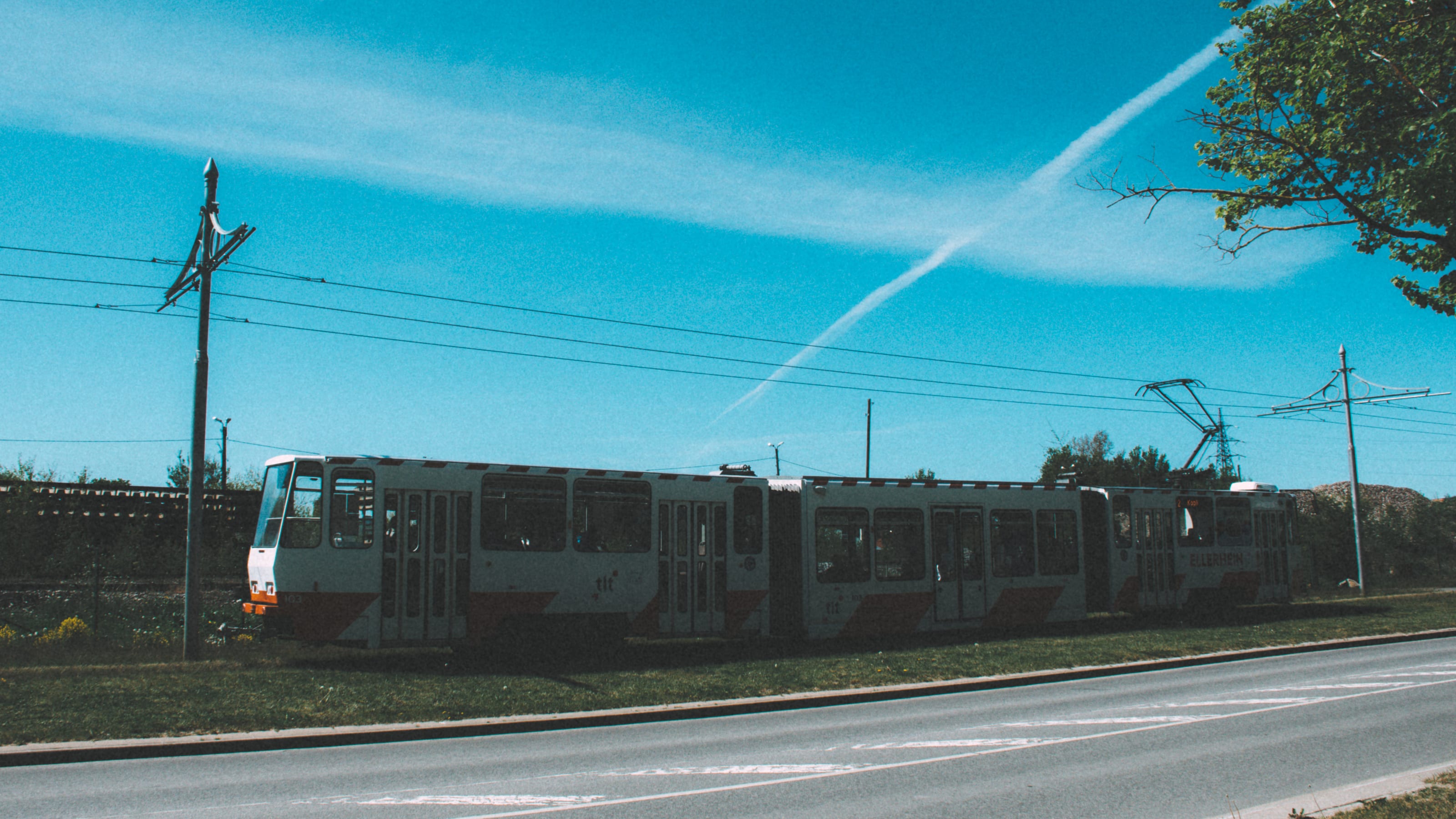Tram crossing an open road under a blue sky in Kopli, Tallinn, Estonia.