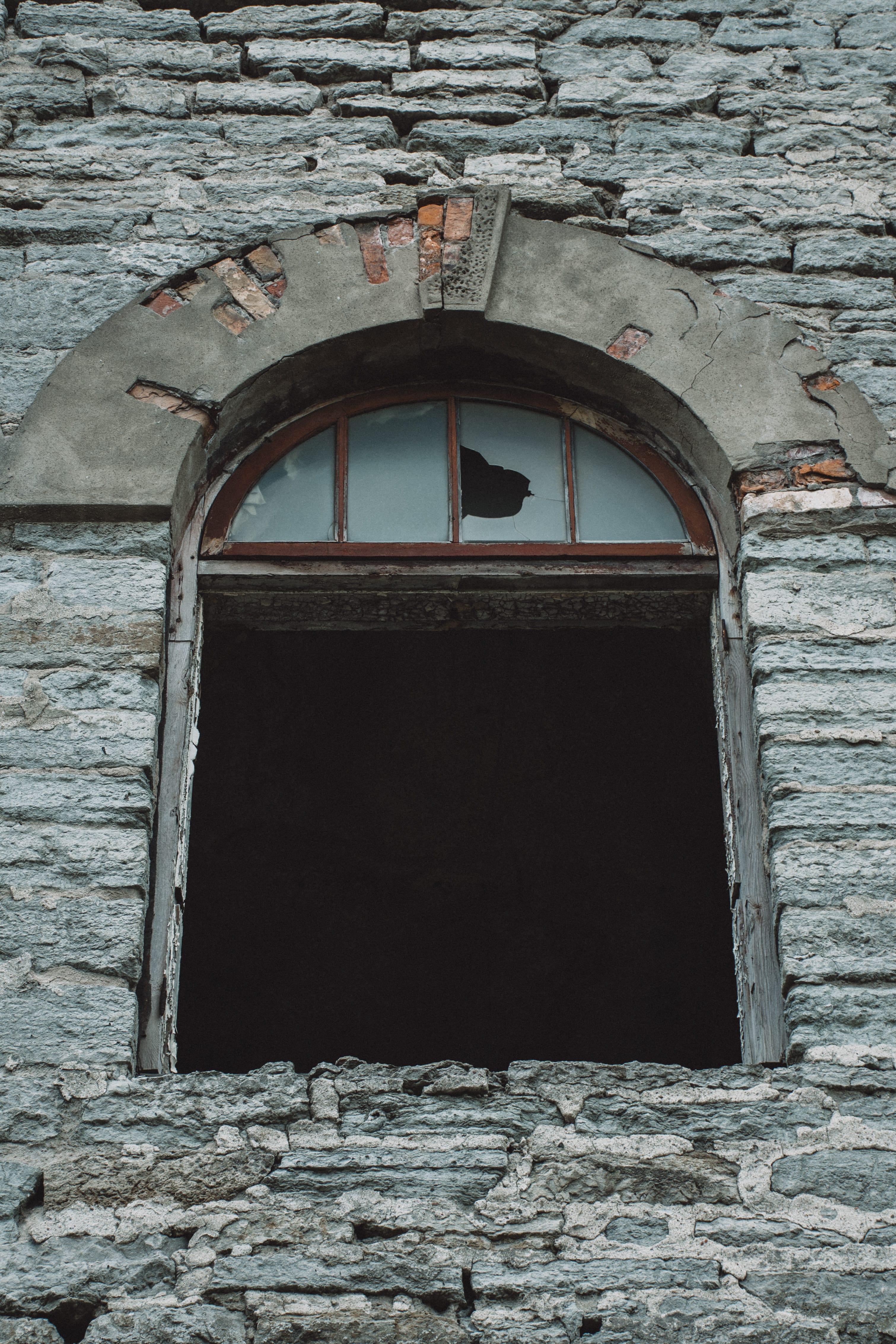 Small arched window in a rough limestone wall in Kopli, Tallinn, Estonia.