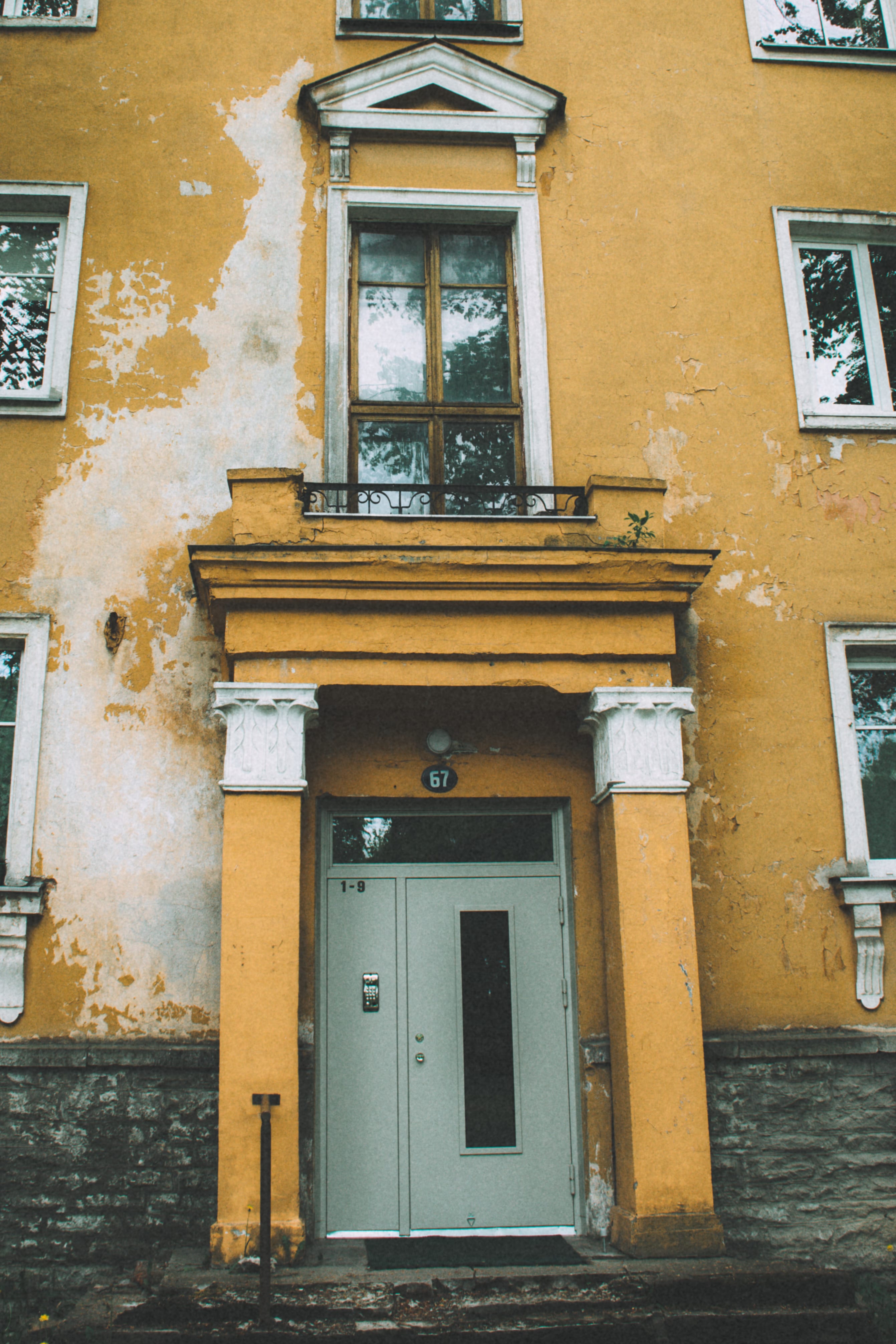 Yellow wooden apartment entrance with a small balcony in Kopli, Tallinn, Estonia.
