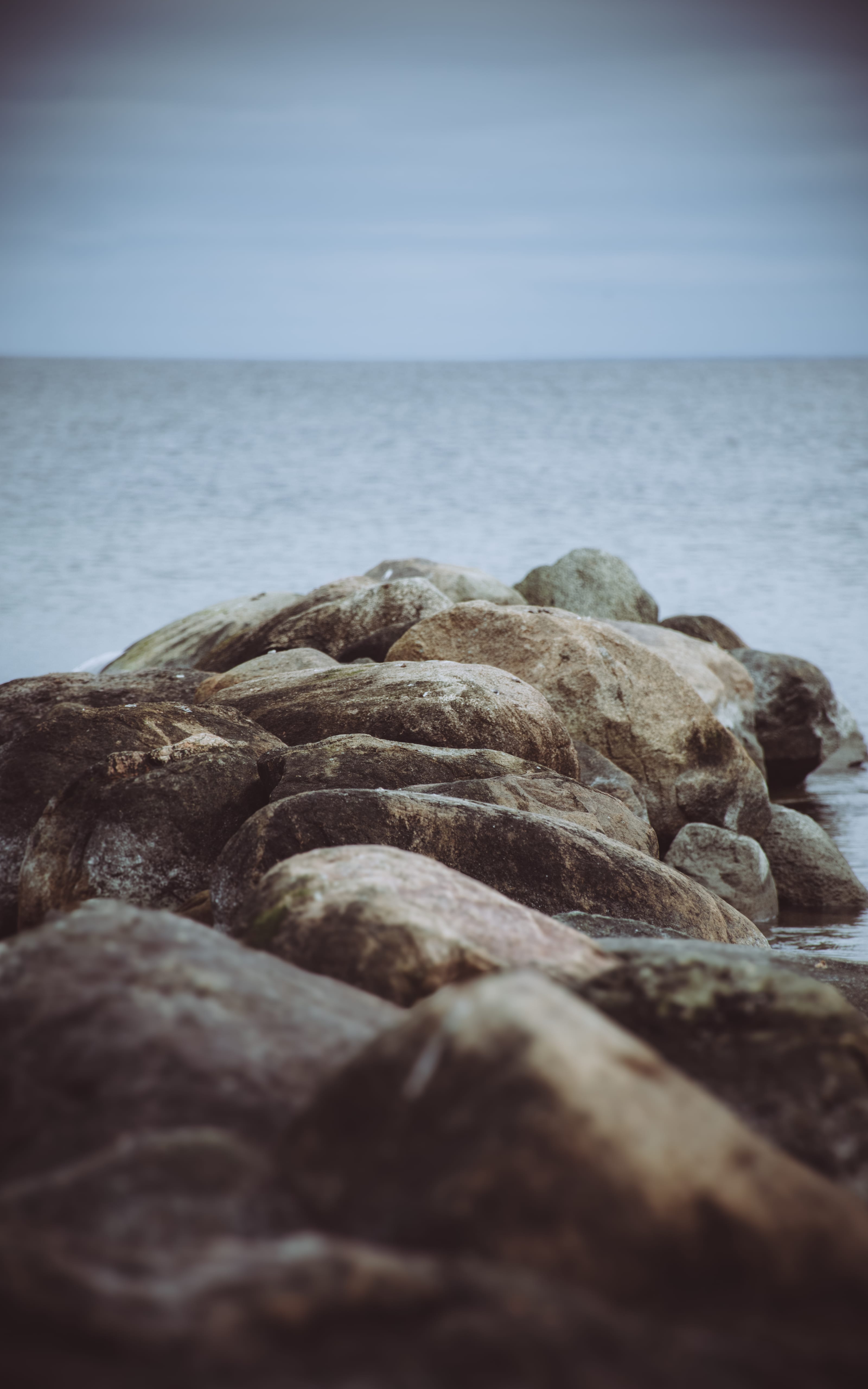 Rounded shoreline rocks beside a calm grey sea in Neeme, Estonia.