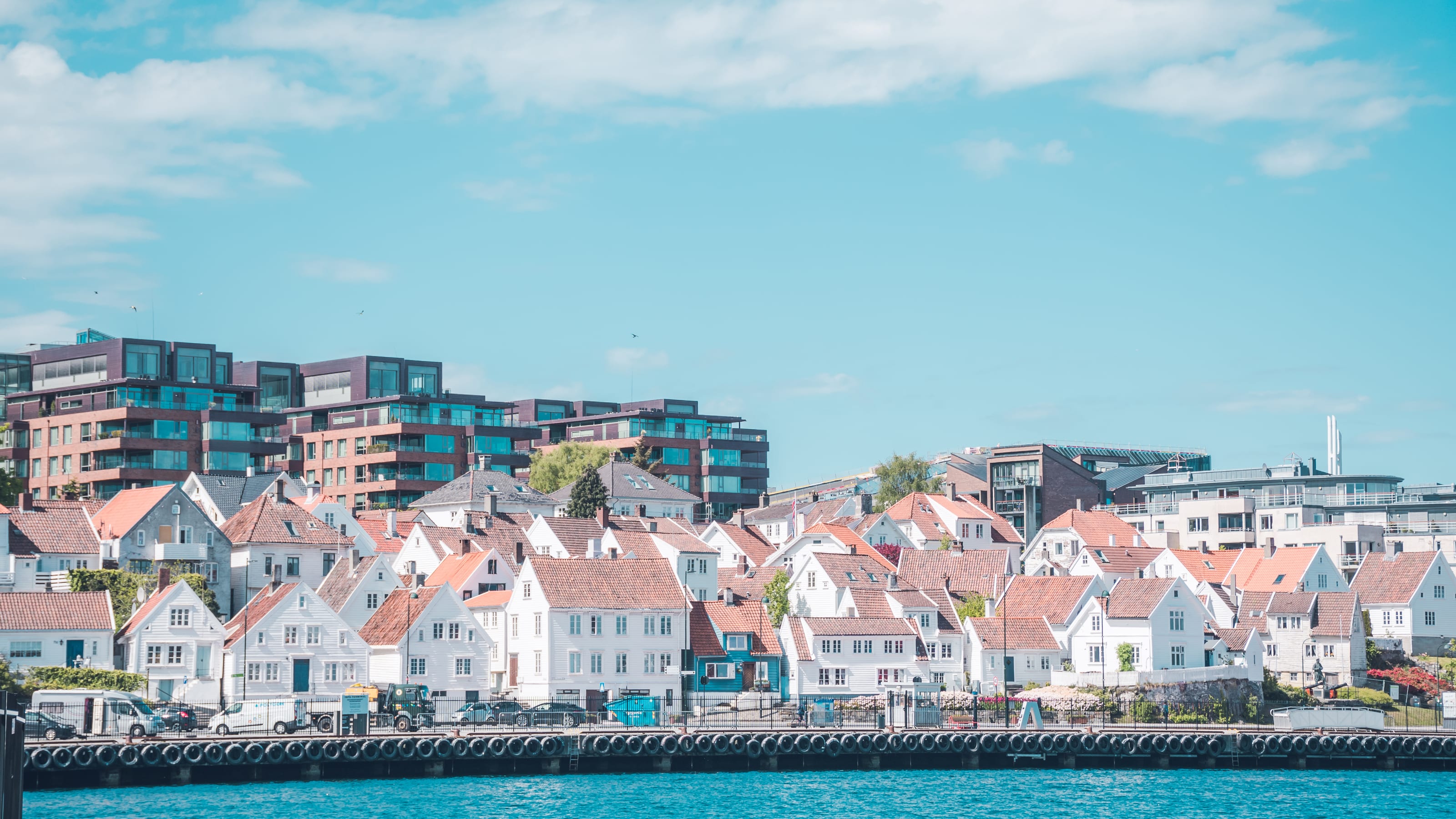 White wooden harbour town lining a sheltered waterfront in coastal Norway.
