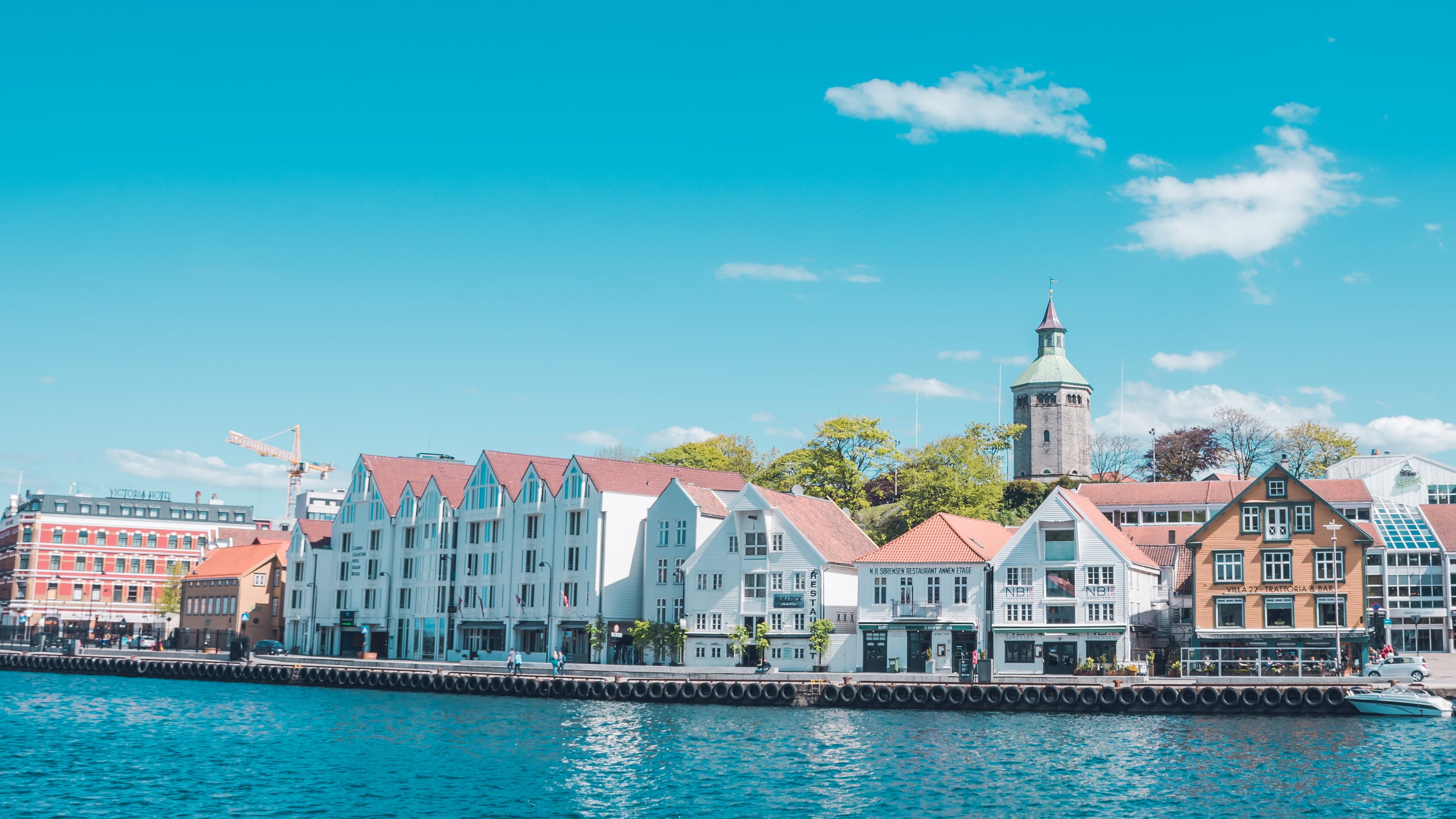 Historic waterfront buildings reflected in turquoise water in coastal Norway.