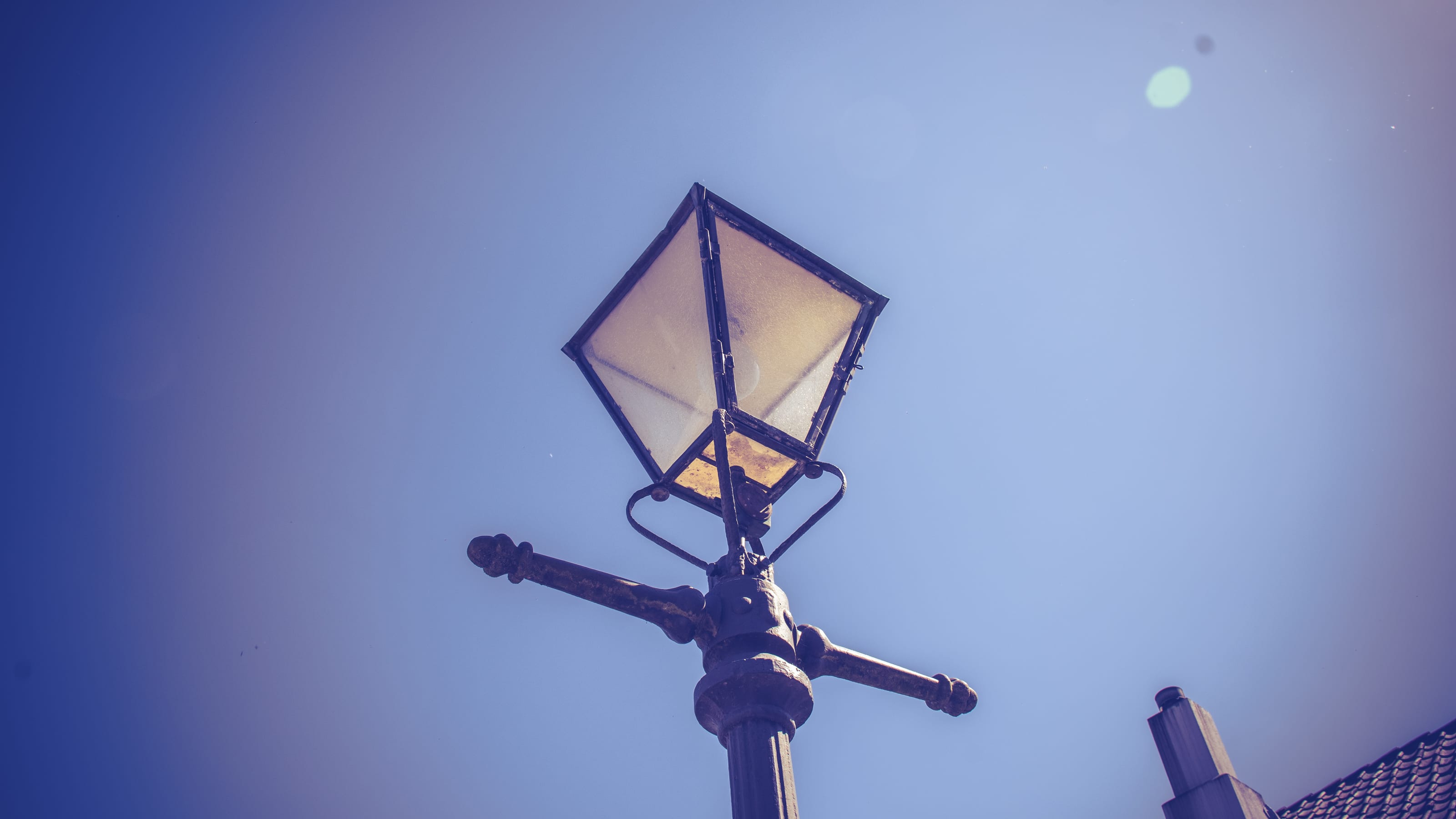 Traditional streetlamp silhouetted against a blue sky in coastal Norway.