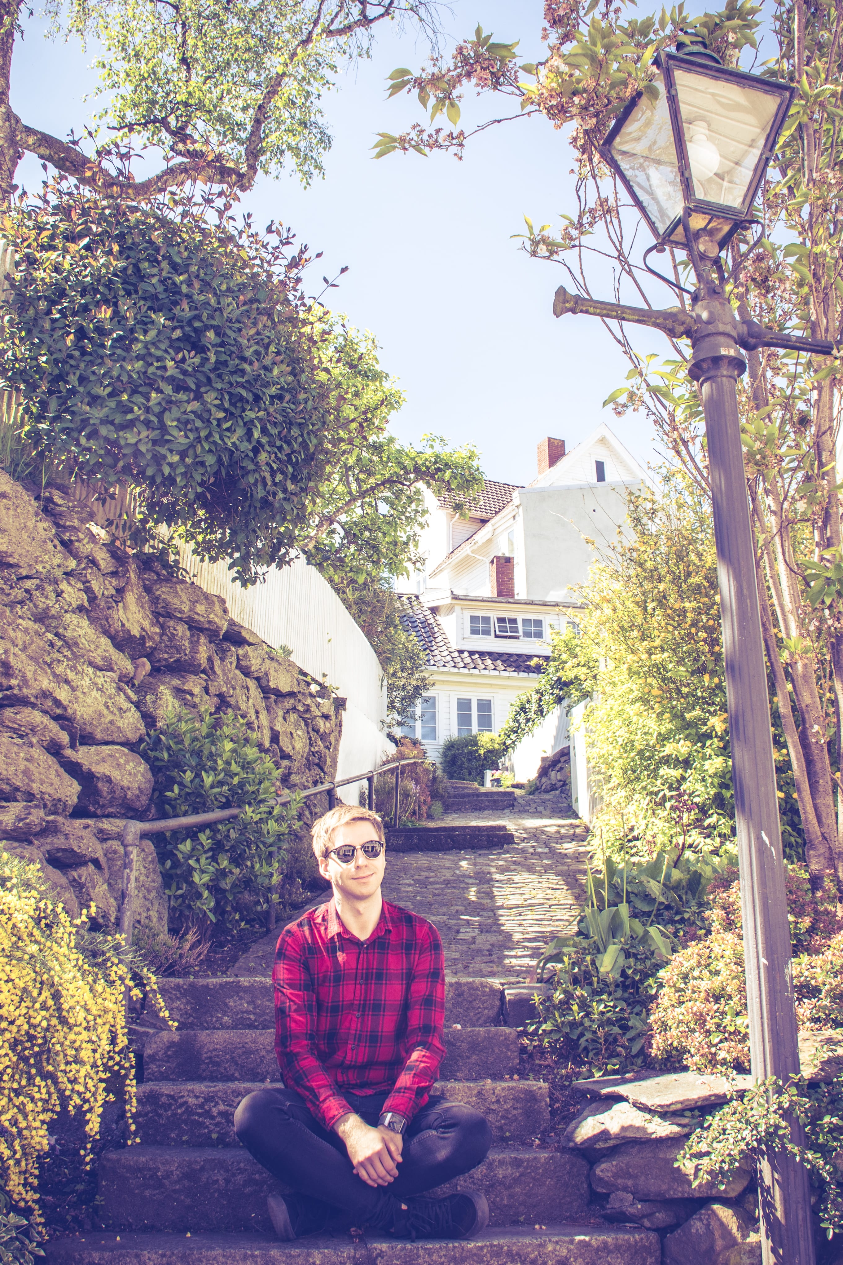 Traveller standing on a rocky path between coastal houses in coastal Norway.