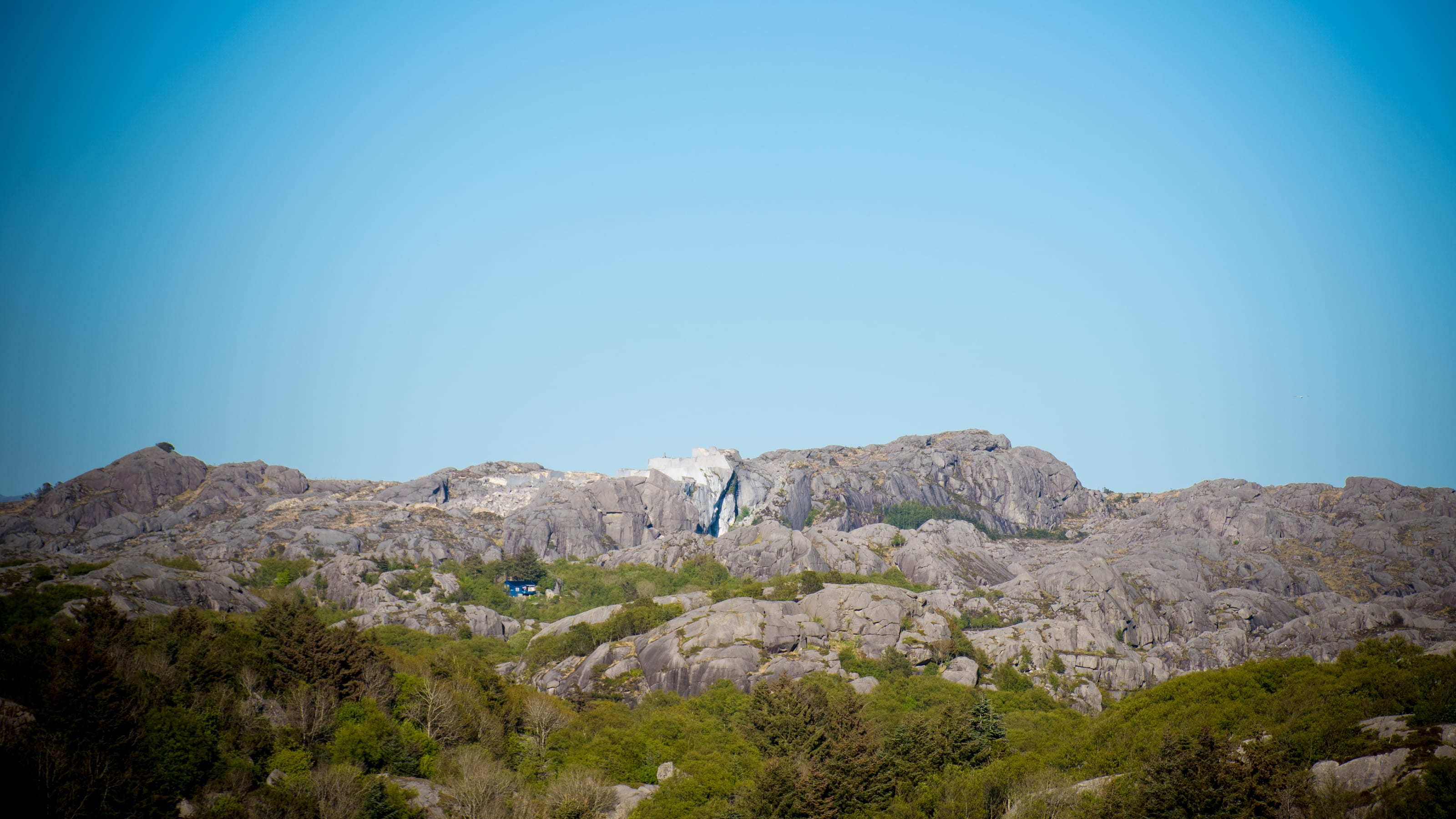 Bare granite ridges beneath a clear northern sky in coastal Norway.