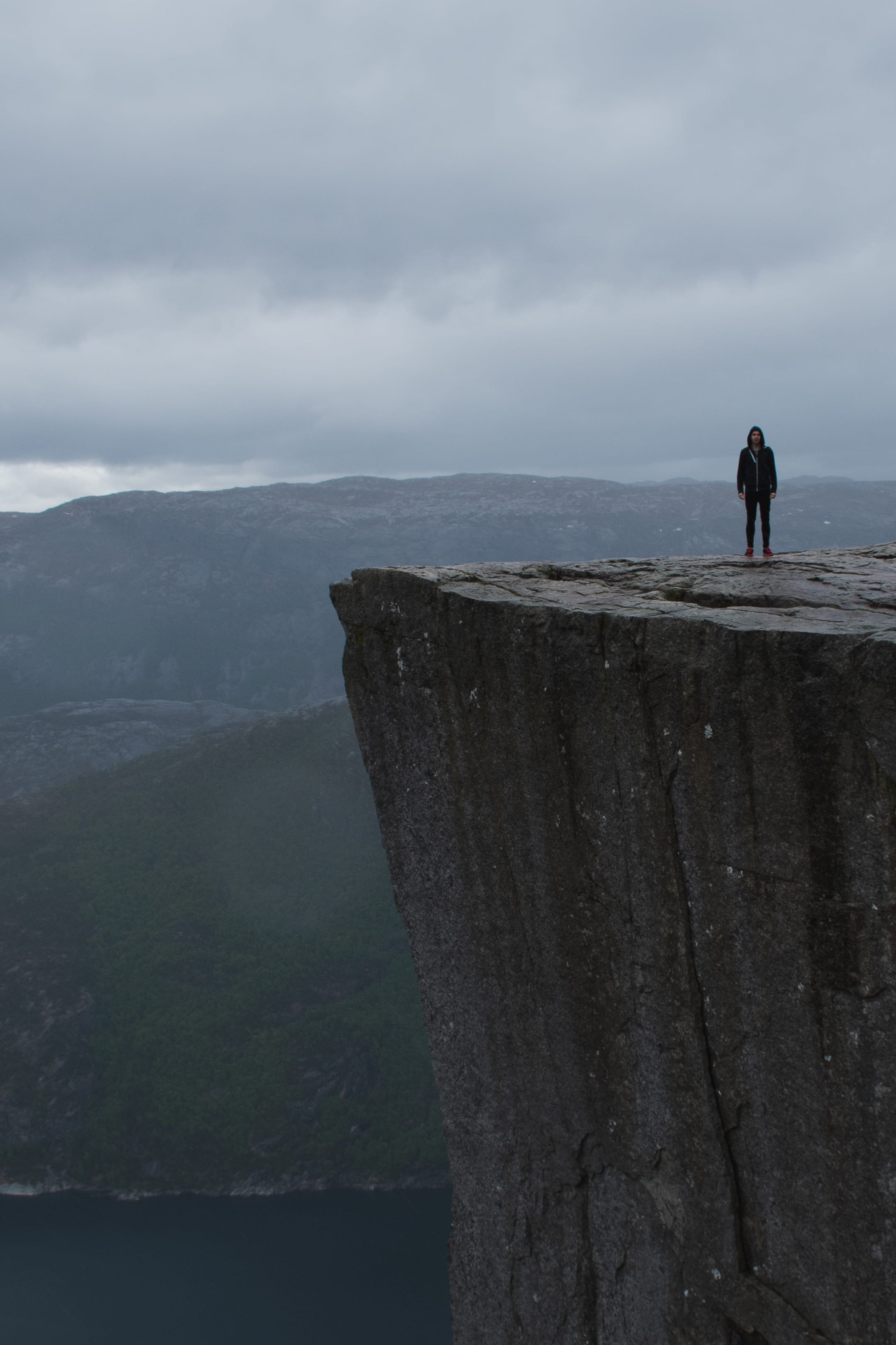 Hiker standing alone on a high concrete viewpoint in coastal Norway.