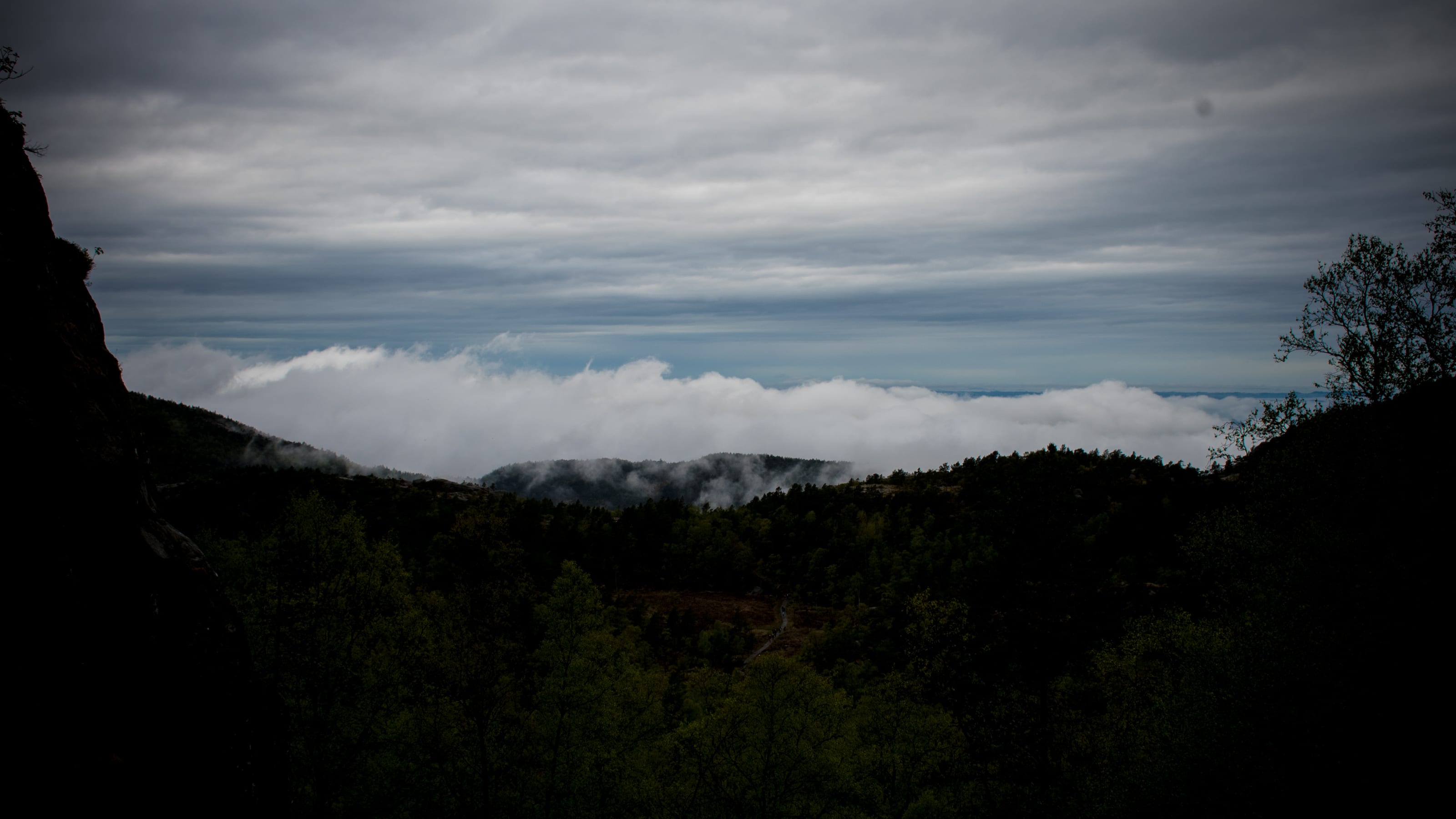 Cloud bank spilling across a dark mountain ridge in coastal Norway.