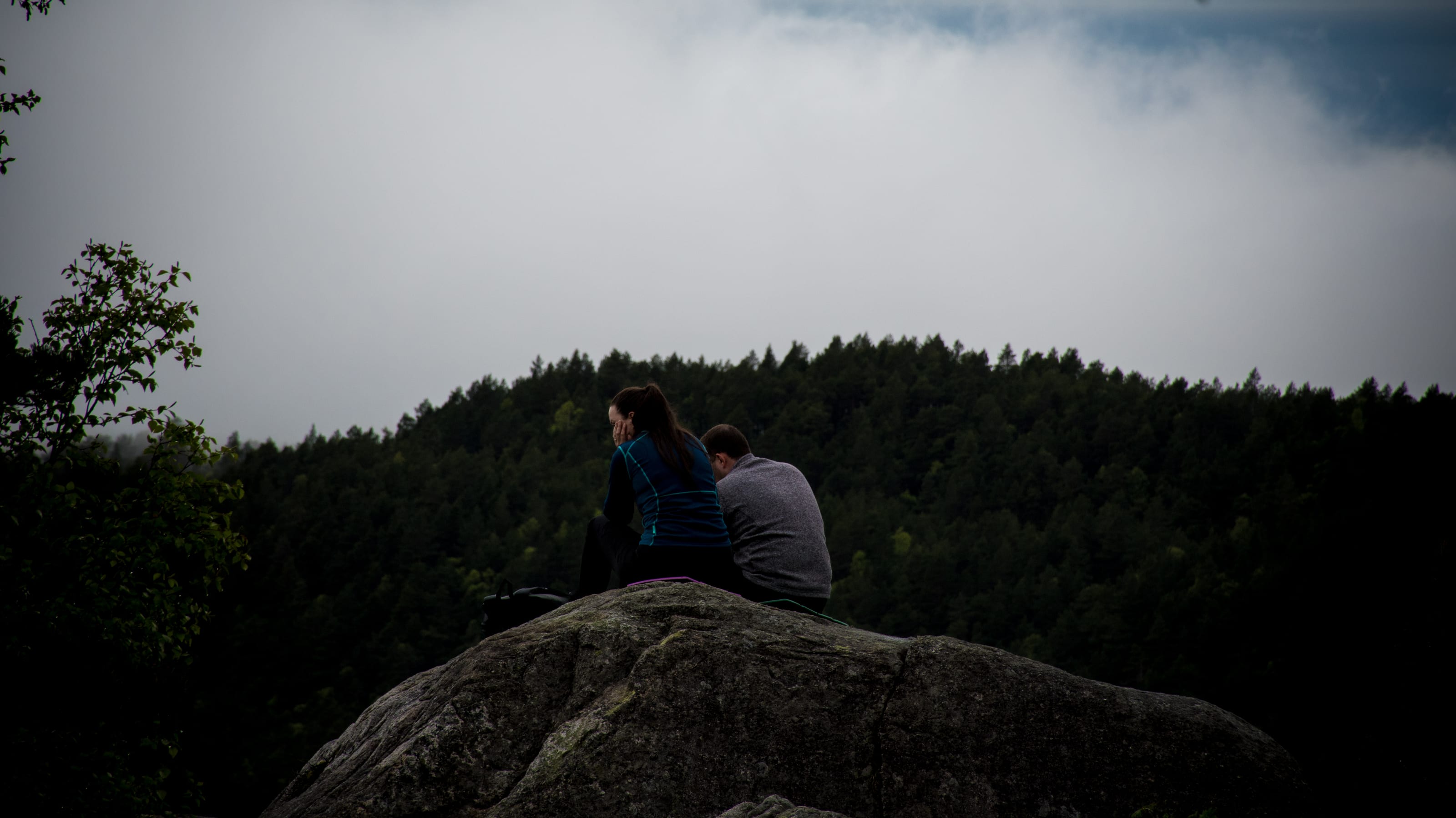 Hiker resting on a rounded granite boulder in coastal Norway.