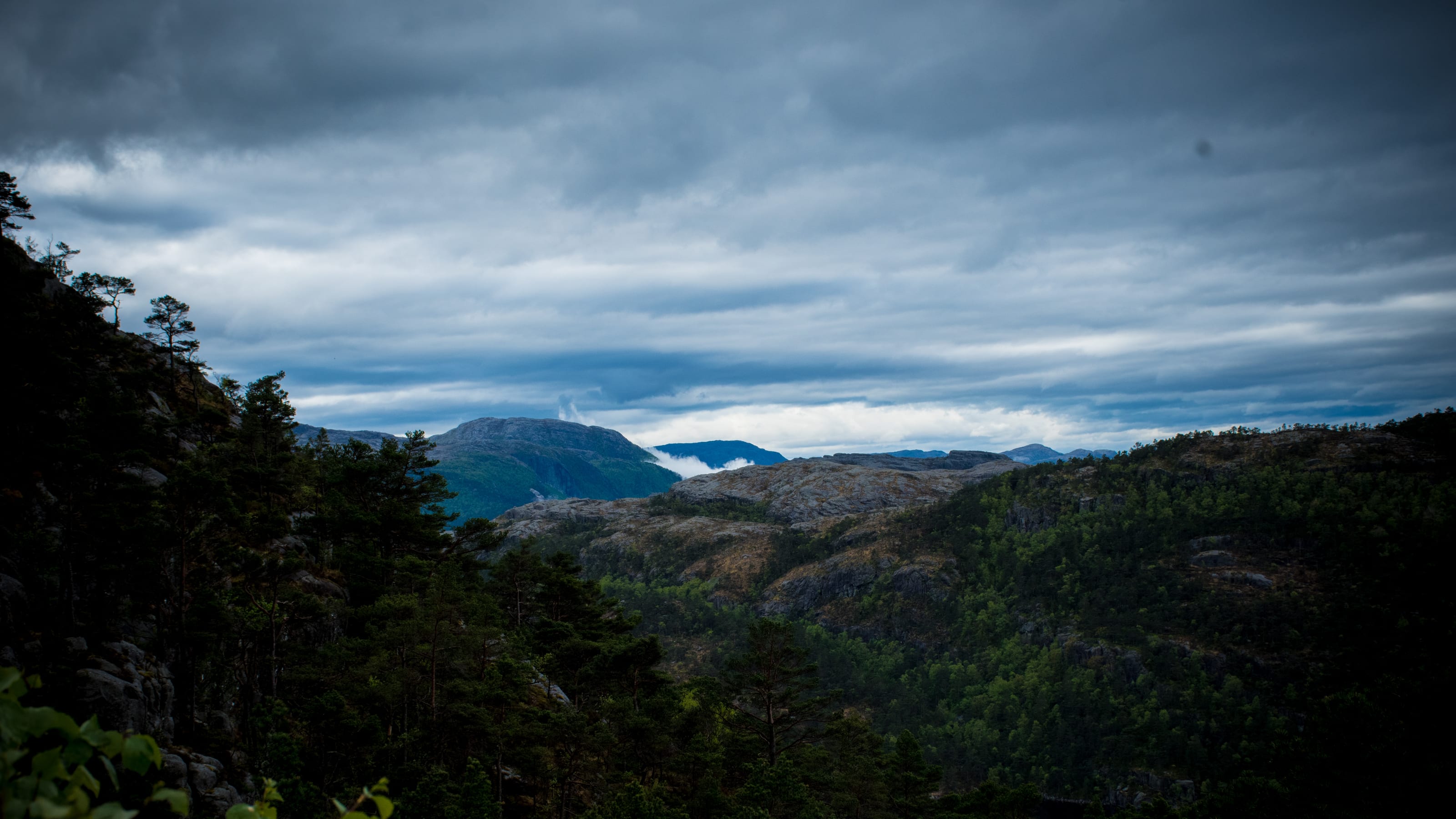 Layered rocky valley beneath a dramatic sky in coastal Norway.