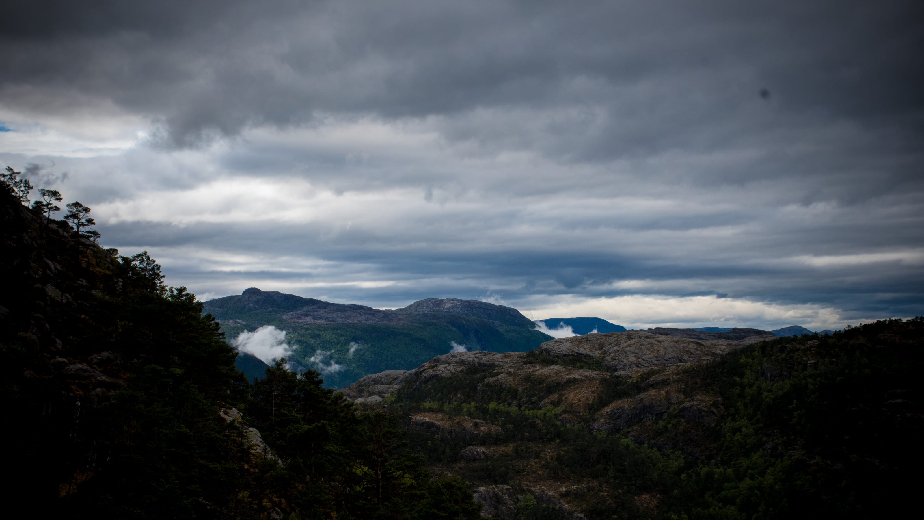 Mountain basin opening toward distant blue ridges in coastal Norway.