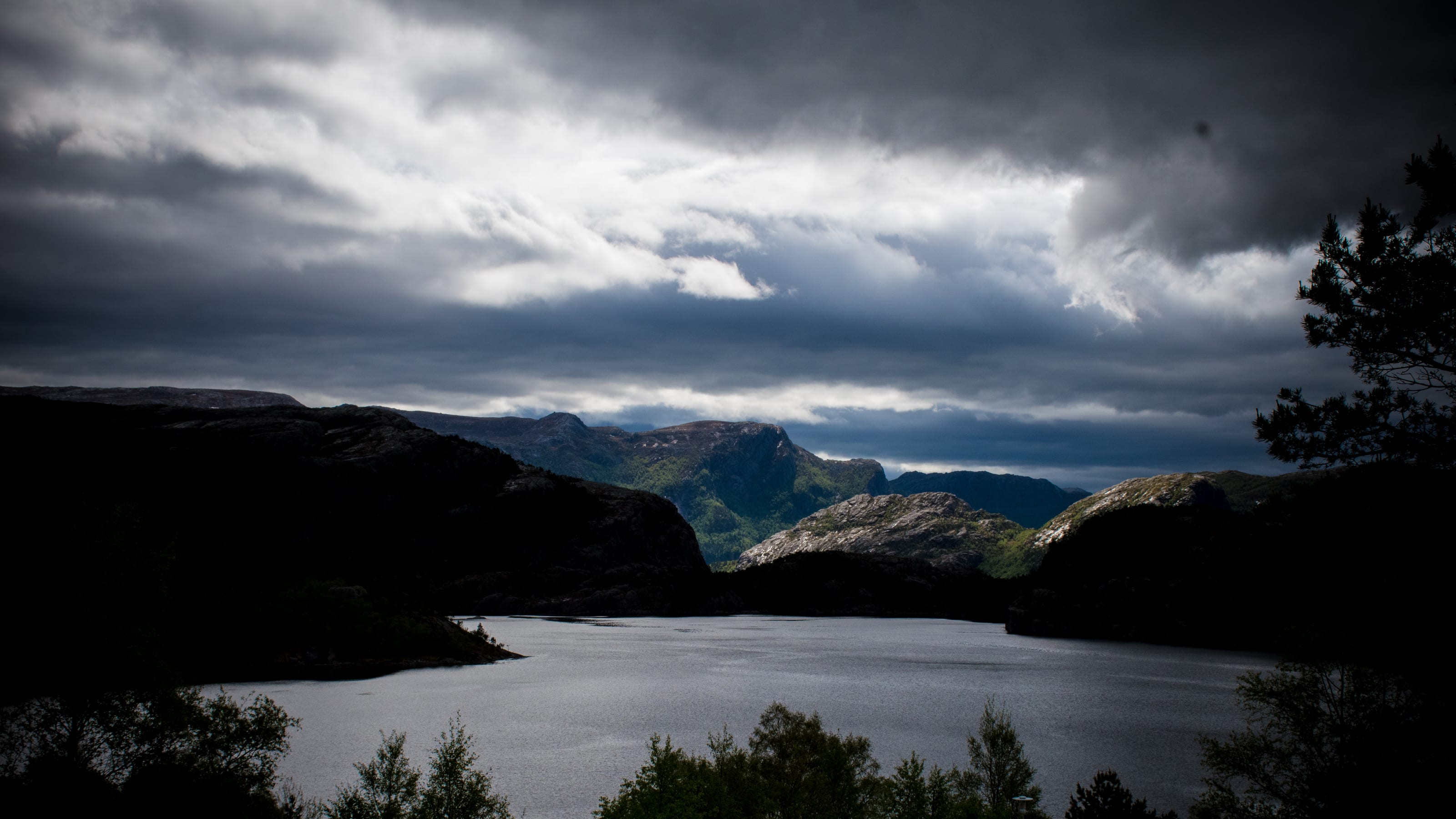 Wide mountain lake framed by shadowed ridges in coastal Norway.
