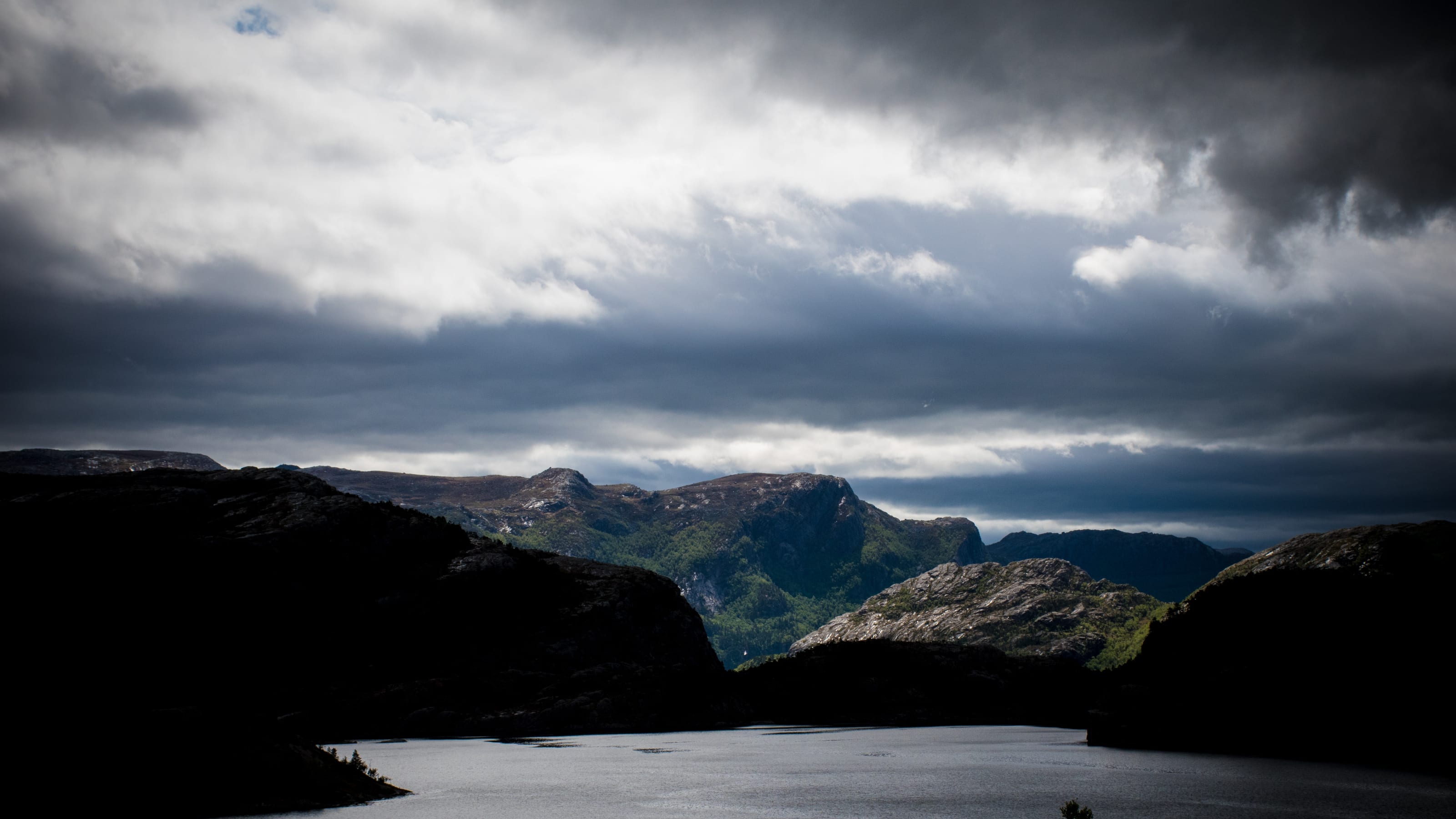 Mountain lake and valley under a breaking storm in coastal Norway.