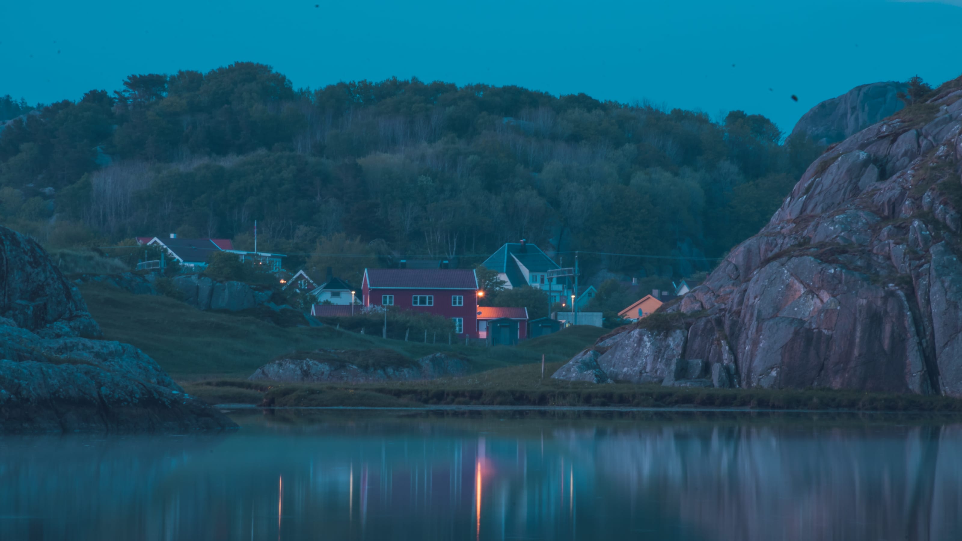 Pink sunset reflected across a still coastal inlet in coastal Norway.