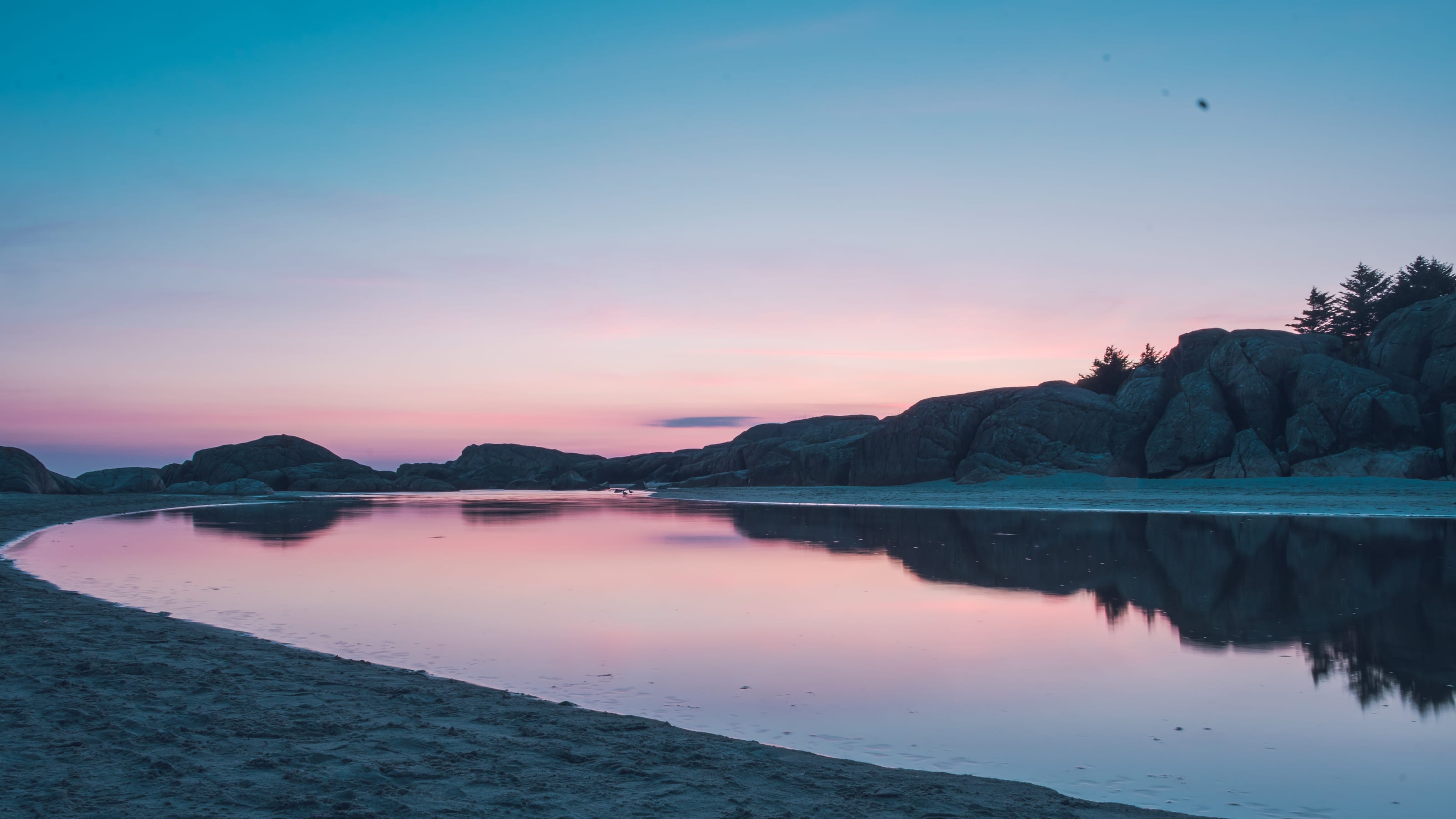 Dark shoreline silhouetted against a pink sunset in coastal Norway.