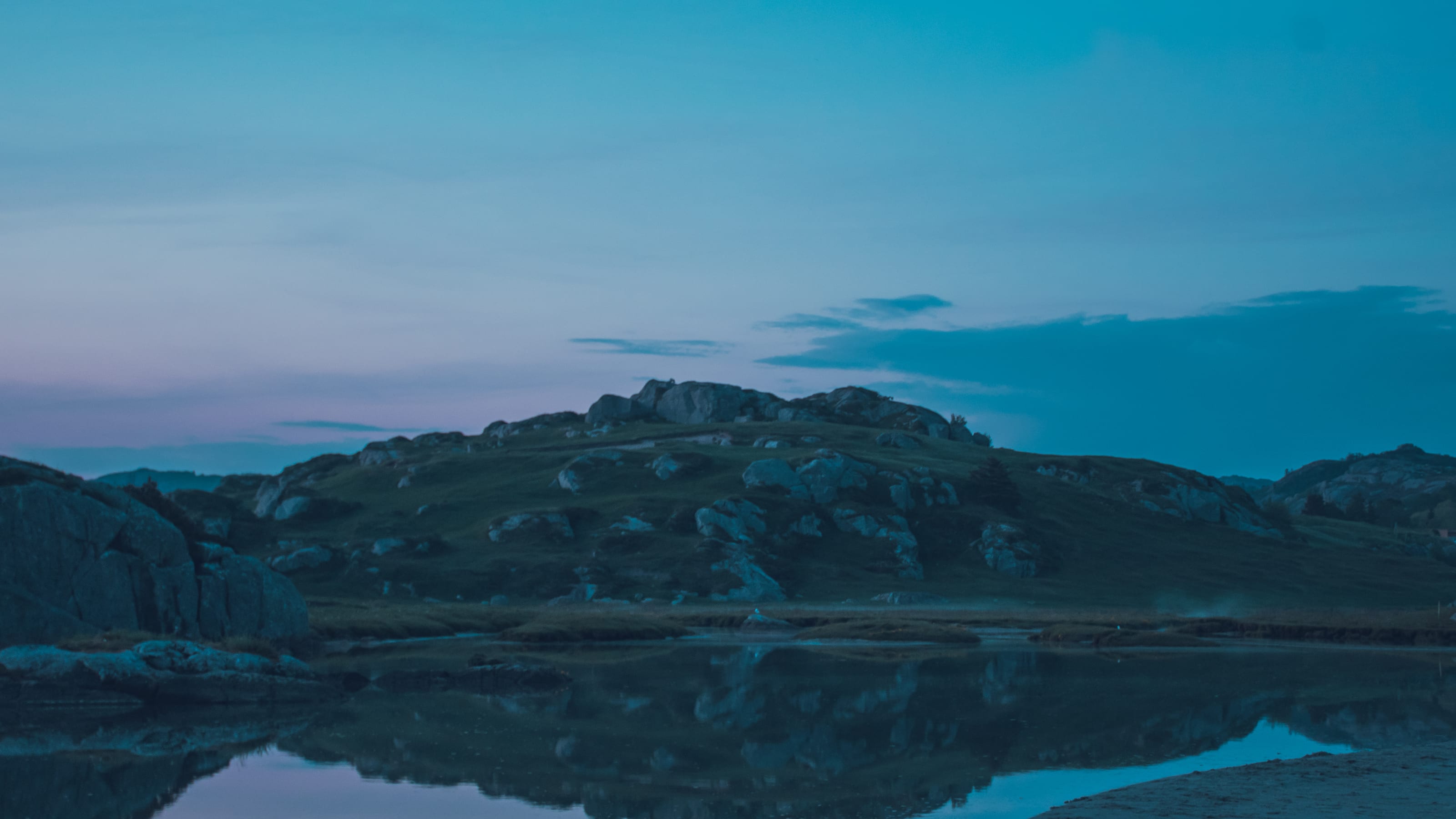 Lit coastal houses under a deep blue evening sky in coastal Norway.
