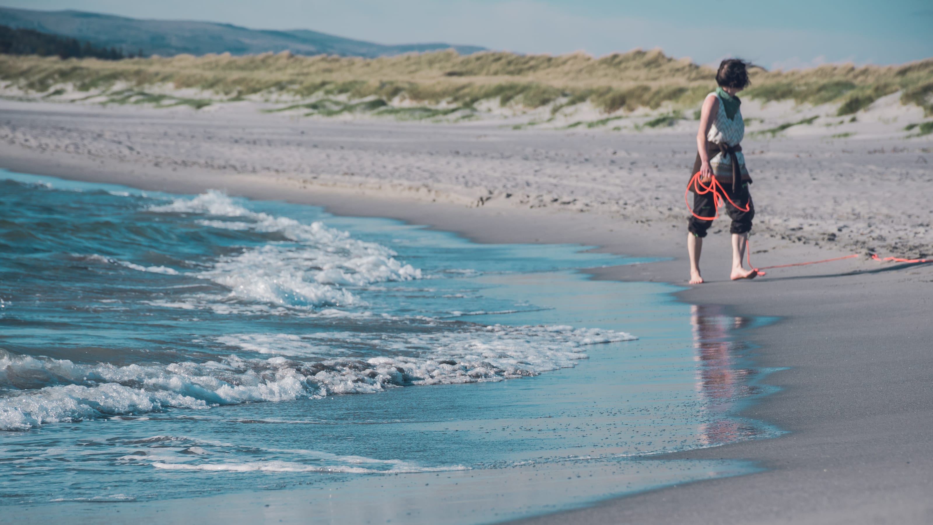White surf rolling toward a pale sandy shore in coastal Norway.