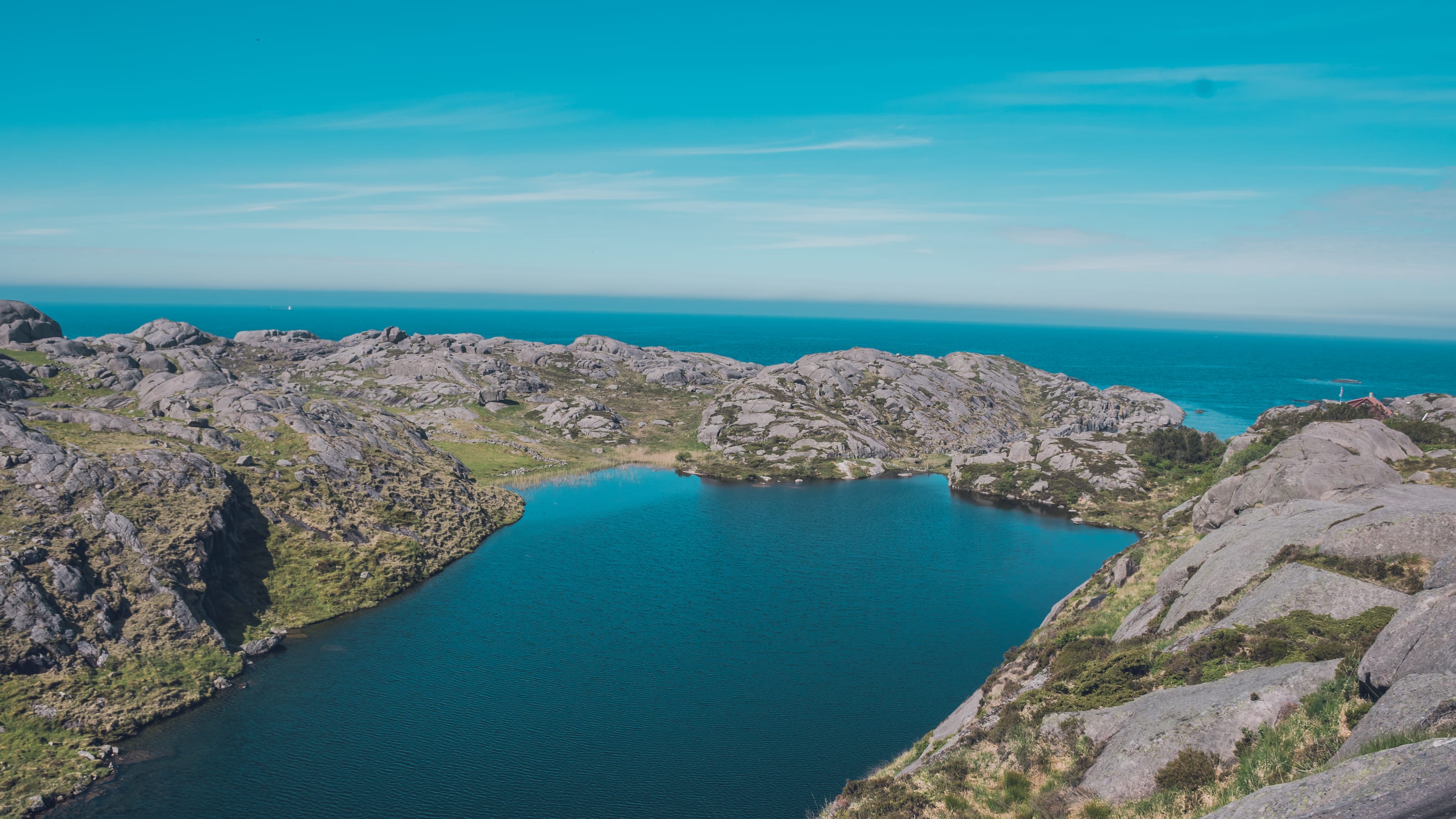 Clear lake set among pale coastal rock formations in coastal Norway.