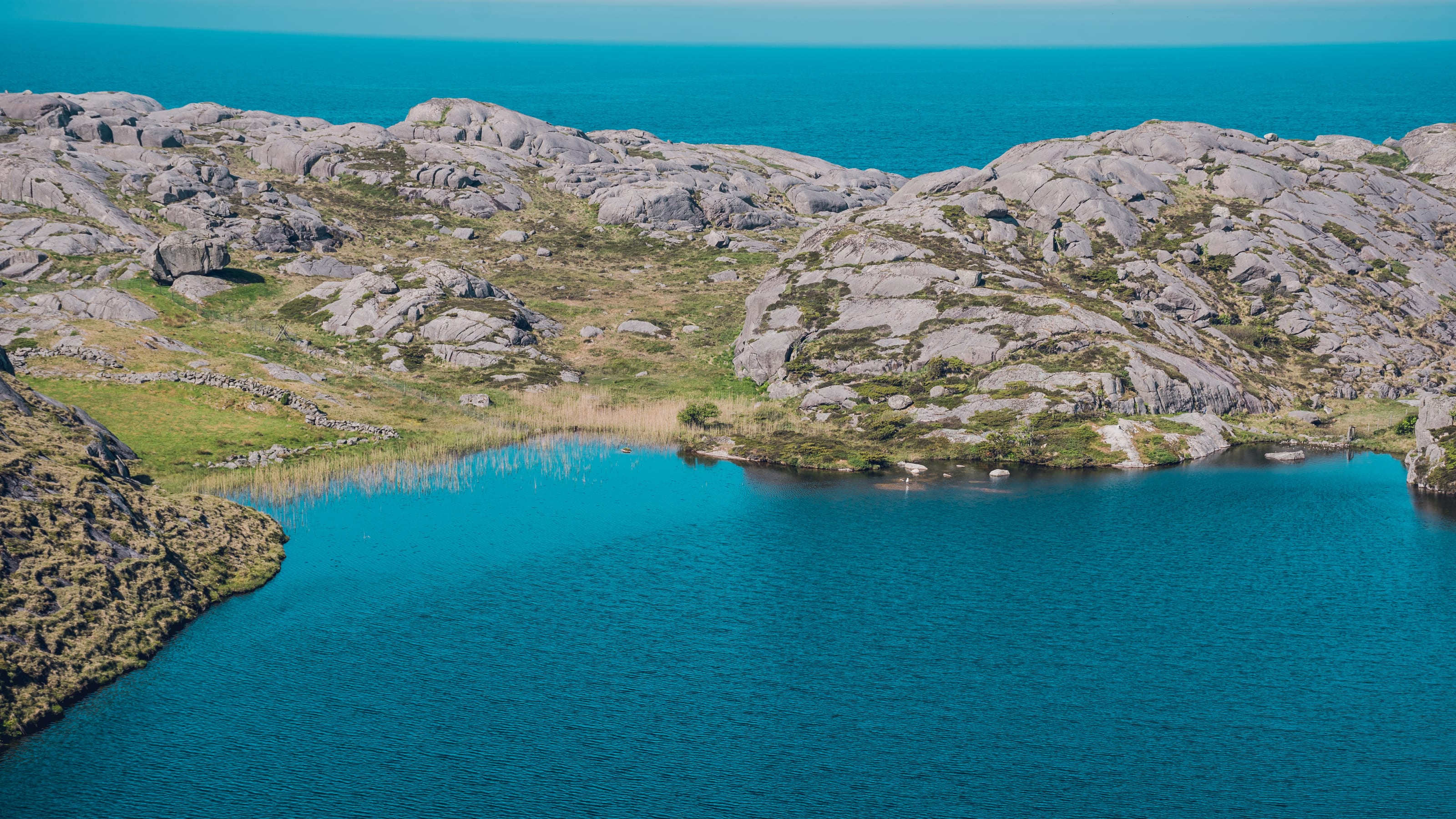 Green valley cutting between rounded granite cliffs in coastal Norway.