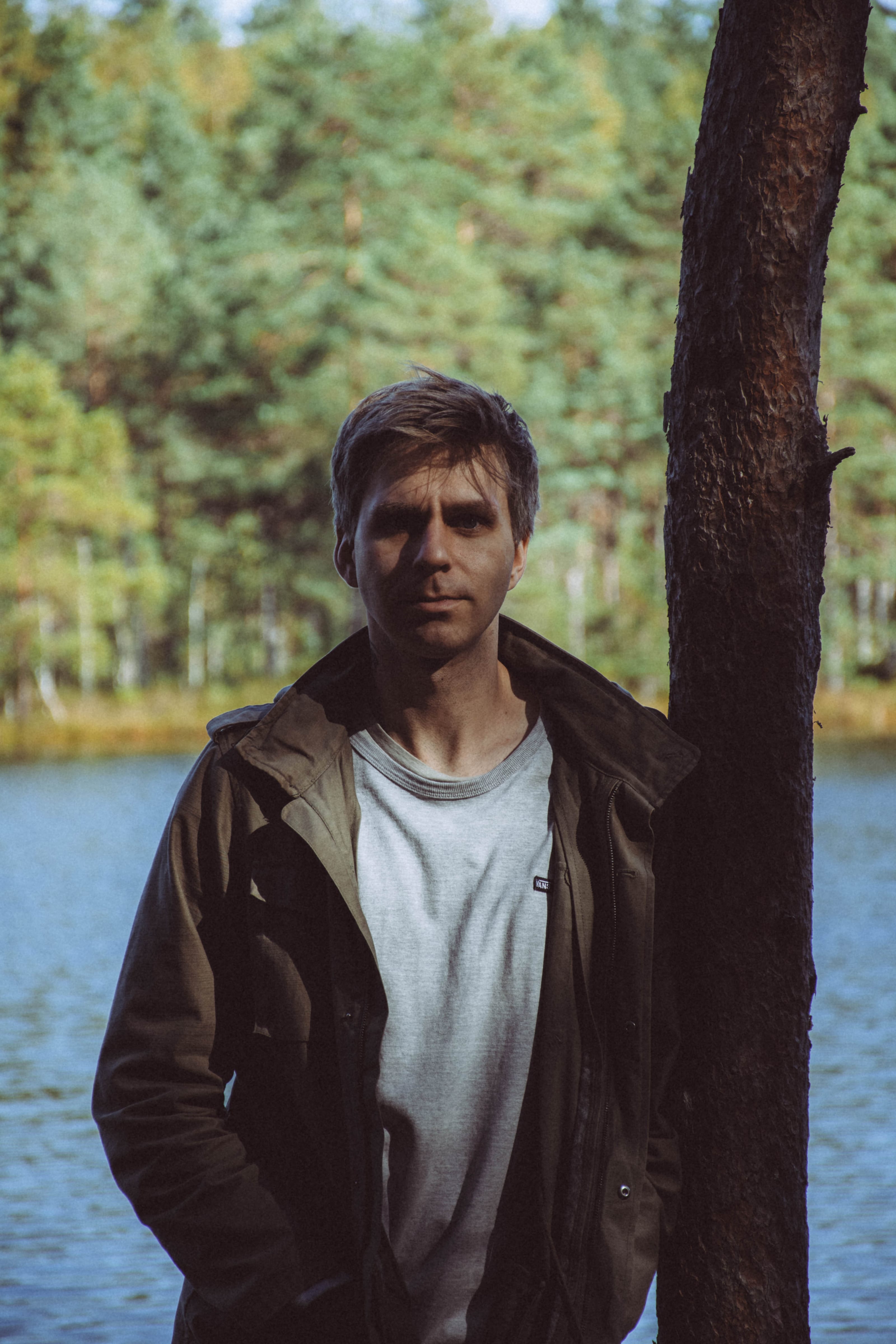 Portrait of a man beside a calm forest lake in Rae Village, Estonia.