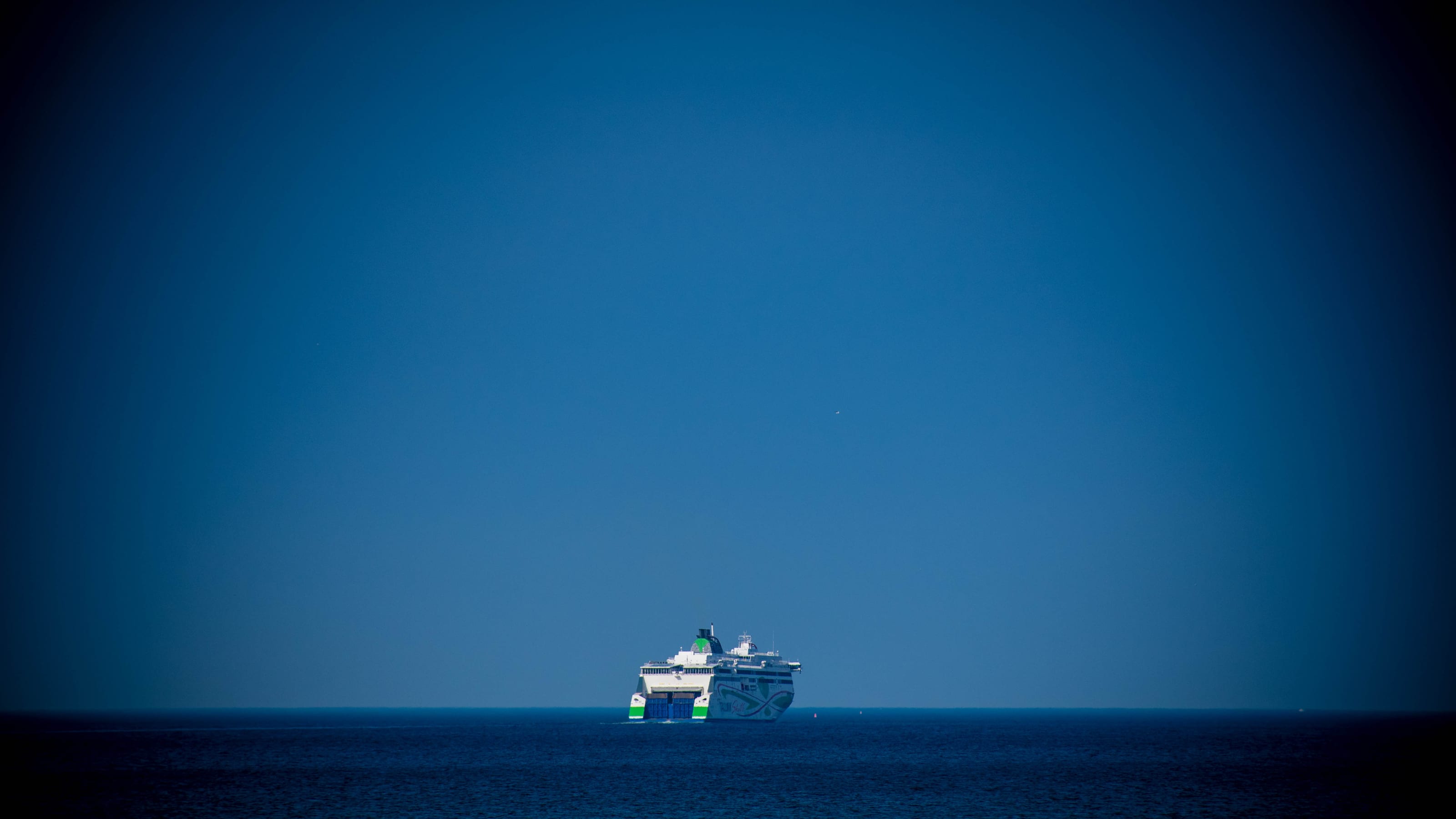 Small white ferry crossing a deep blue sea beneath an open sky